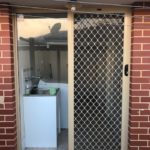 Laundry Sliding Securegrille security door fitted on a red brick house in classi cream frame