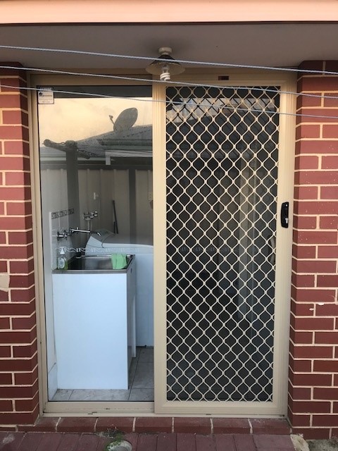 Laundry Sliding Securegrille security door fitted on a red brick house in classi cream frame