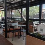 Outdoor Dining area with tables and chairs set, outdoor blinds by nu style shutters are seen in the background enclosing the area from the busy street