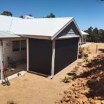 shows farm styled home on hill with ziptrak blinds installed